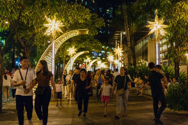 Bonifacio High Street lined with towering illuminated Christmas light installations and crowds strolling at night